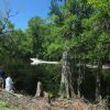 Boys fishing on river bank with boat driving by